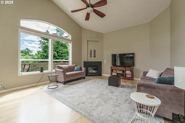 1216 SE 47th St, Hillsboro, OR 97123 - living room with wood finished floors, a ceiling fan, a glass covered fireplace, high vaulted ceiling, and baseboards