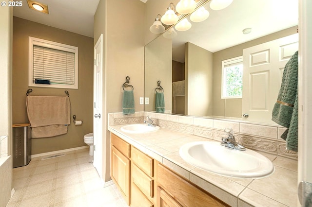 1216 SE 47th St, Hillsboro, OR 97123 - bathroom featuring double vanity, toilet, baseboards, and a chandelier