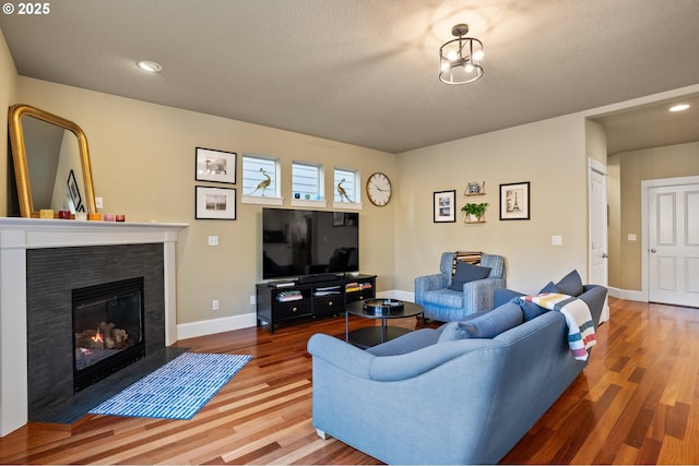 living area with wood finished floors, a fireplace with flush hearth, baseboards, and recessed lighting
