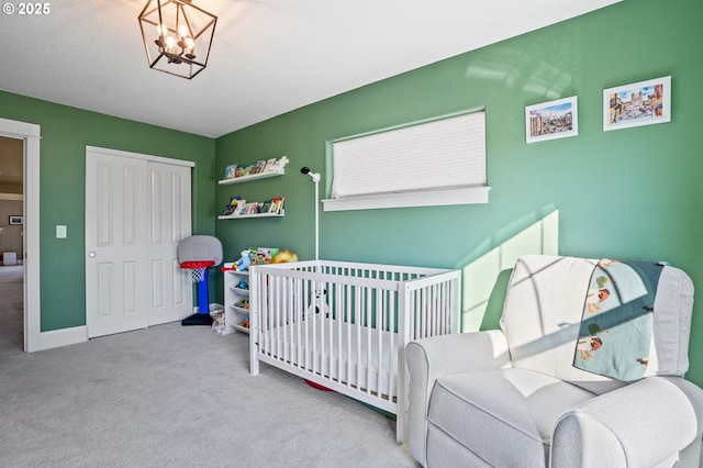 carpeted bedroom with a chandelier, a crib, and a closet