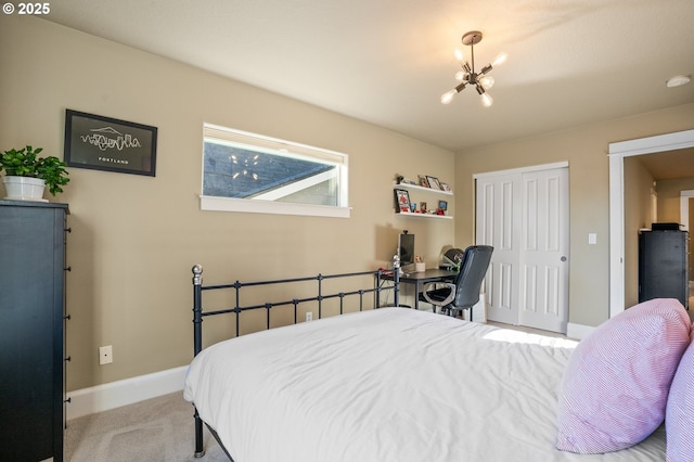 carpeted bedroom with a chandelier, a closet, and baseboards