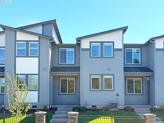 back of property featuring metal roof, cooling unit, and a standing seam roof