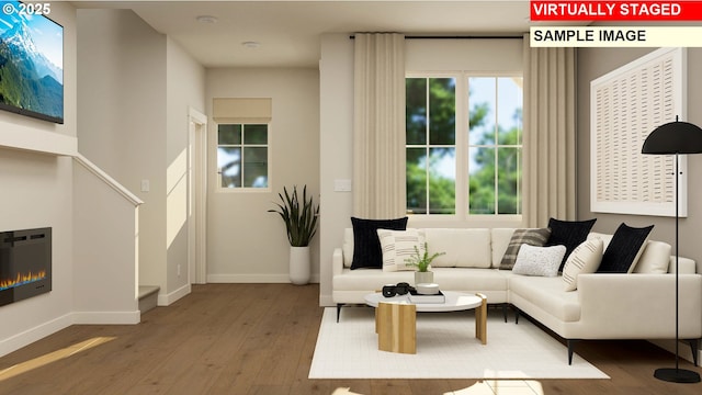 living room with baseboards, a glass covered fireplace, and hardwood / wood-style flooring