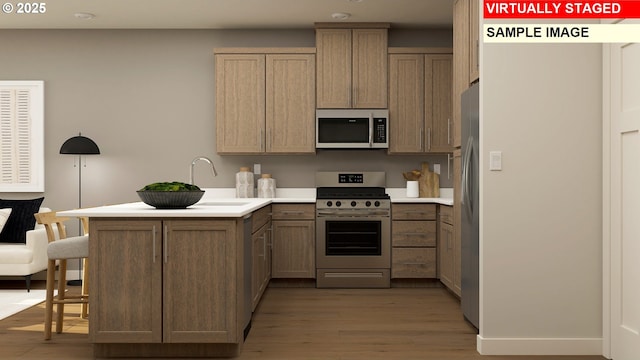kitchen with light wood-style flooring, a sink, a kitchen bar, a peninsula, and appliances with stainless steel finishes
