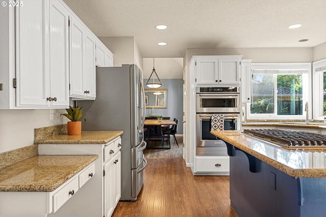 8967 SW Leslie St, Portland, OR 97223 - kitchen with stainless steel appliances, a sink, wood finished floors, white cabinets, and recessed lighting