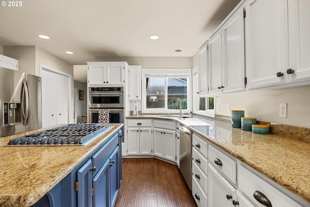 8967 SW Leslie St, Portland, OR 97223 - kitchen with blue cabinetry, stainless steel appliances, a sink, white cabinetry, and dark wood-type flooring