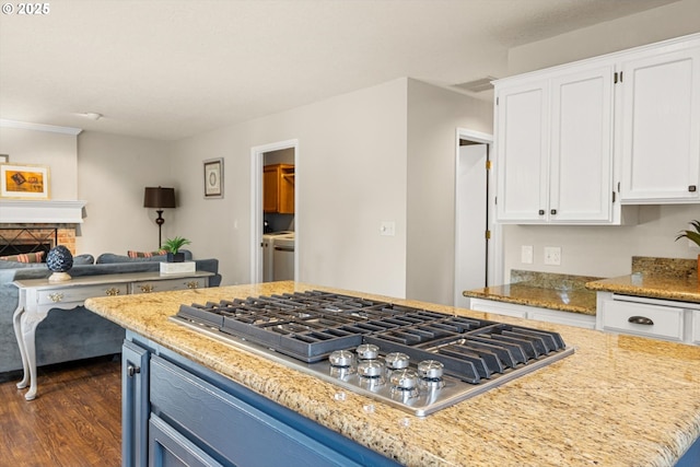 8967 SW Leslie St, Portland, OR 97223 - kitchen with stainless steel gas cooktop, white cabinets, dark wood-style floors, light stone countertops, and a fireplace
