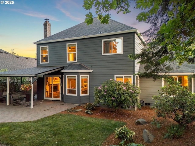 8967 SW Leslie St, Portland, OR 97223 - back of house at dusk with a chimney, a shingled roof, a yard, and a patio
