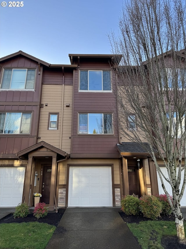 view of property featuring board and batten siding, driveway, and an attached garage