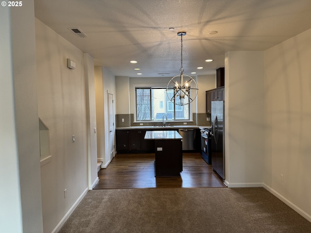 kitchen featuring a center island, decorative light fixtures, light countertops, visible vents, and dark brown cabinetry