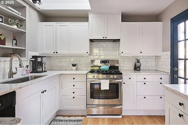 kitchen featuring stainless steel gas range oven, dishwashing machine, white cabinetry, and a sink