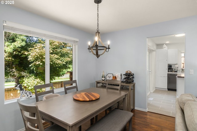 dining room with baseboards, an inviting chandelier, and light wood-style floors