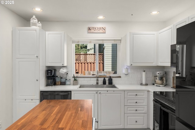 kitchen with white cabinetry, tasteful backsplash, a sink, wood counters, and black appliances