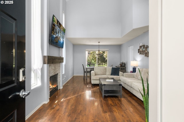 living area with a fireplace, dark wood-style flooring, and a towering ceiling