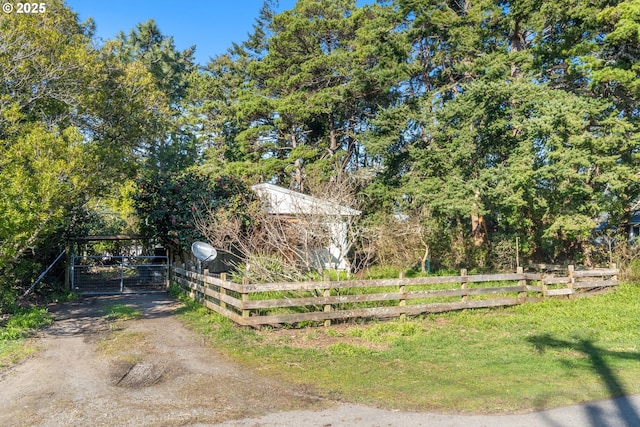 view of yard with dirt driveway, fence, and a carport