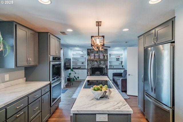6132 Wilford Pl SW, Albany, OR 97321 - kitchen featuring appliances with stainless steel finishes, open floor plan, gray cabinetry, a center island, and dark wood-style floors