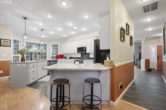 kitchen with kitchen peninsula, appliances with stainless steel finishes, pendant lighting, and a breakfast bar area