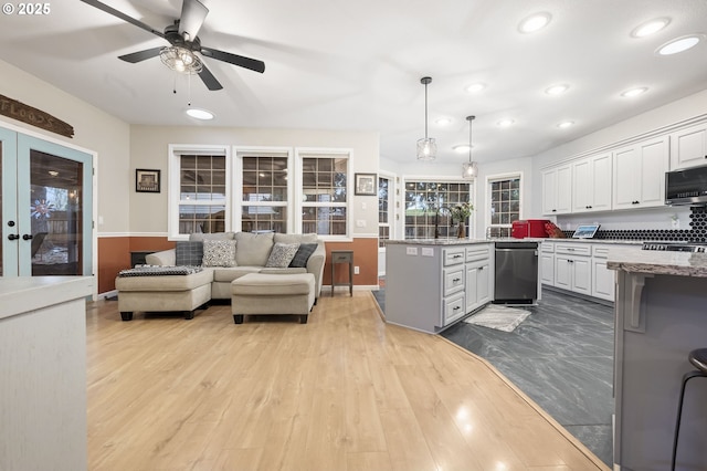 kitchen with white cabinets, stainless steel appliances, light stone counters, and hanging light fixtures