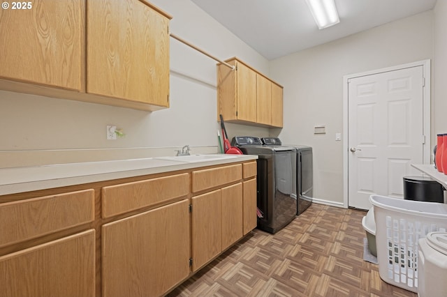 laundry area featuring washing machine and clothes dryer, sink, cabinets, and parquet flooring