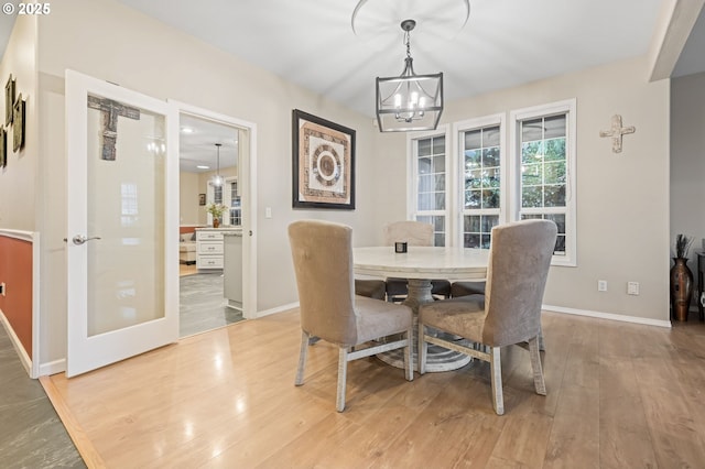 dining space with light hardwood / wood-style floors and an inviting chandelier