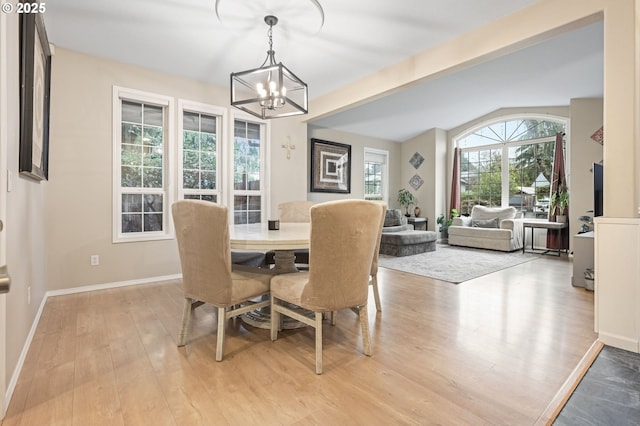 dining space with beamed ceiling, light hardwood / wood-style floors, and a notable chandelier