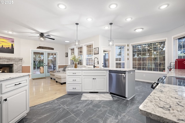 kitchen featuring french doors, white cabinets, sink, hanging light fixtures, and stainless steel dishwasher