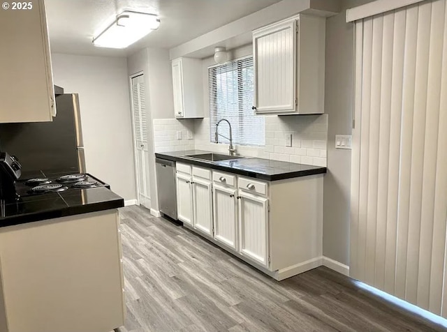 8416 SE Insley St, Portland, OR 97266 - kitchen with stainless steel appliances, light wood-style floors, a sink, and dark countertops