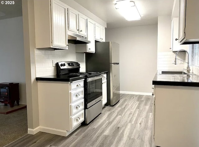 8416 SE Insley St, Portland, OR 97266 - kitchen featuring stainless steel electric range, under cabinet range hood, a wood stove, light wood finished floors, and a sink