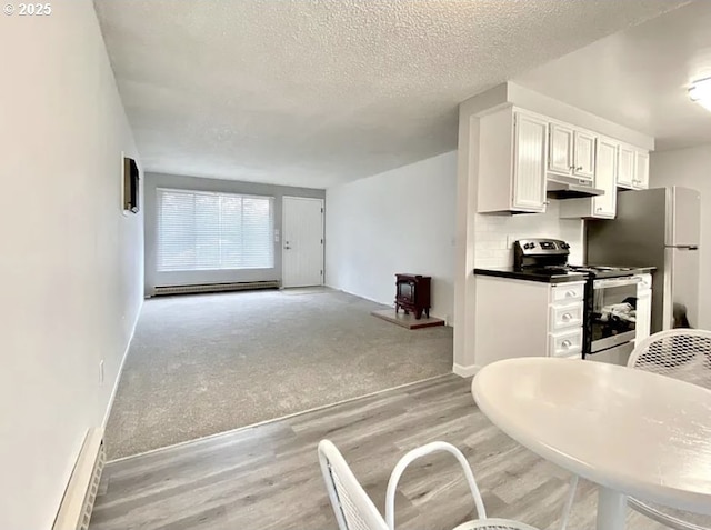 8416 SE Insley St, Portland, OR 97266 - kitchen featuring light wood-style flooring, white cabinetry, stainless steel range with electric stovetop, under cabinet range hood, and a baseboard radiator