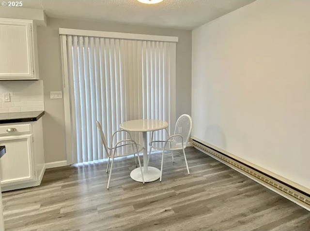8416 SE Insley St, Portland, OR 97266 - unfurnished dining area featuring baseboards, a textured ceiling, wood finished floors, and baseboard heating