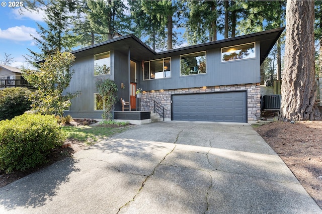 view of front facade featuring a garage, stone siding, and driveway