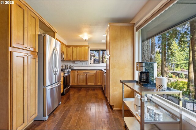 kitchen featuring tasteful backsplash, brown cabinets, appliances with stainless steel finishes, a wood stove, and dark wood-style floors