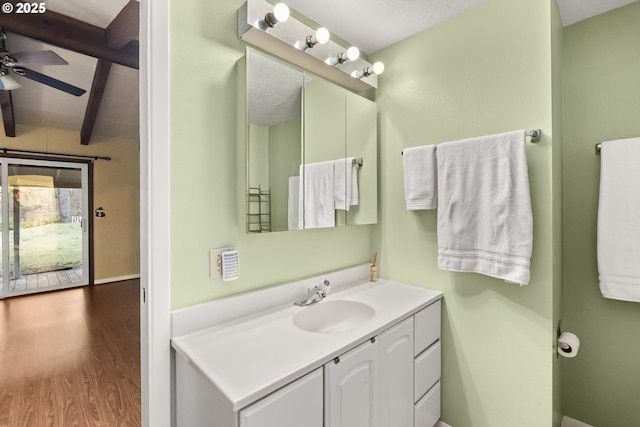 bathroom featuring vanity, ceiling fan, wood-type flooring, and beamed ceiling