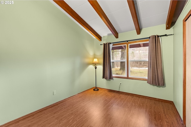 empty room with vaulted ceiling with beams and wood-type flooring