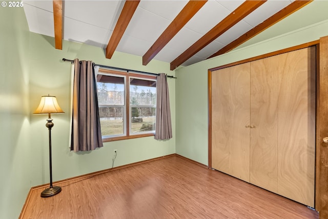 unfurnished bedroom with vaulted ceiling with beams, light hardwood / wood-style floors, and a closet