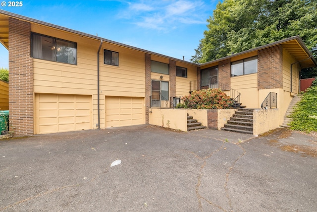 16739 NE Glisan St, Gresham, OR 97230 - townhome / multi-family property featuring asphalt driveway, an attached garage, brick siding, and stairs