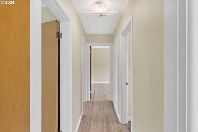hallway with attic access, light wood-style floors, and baseboards