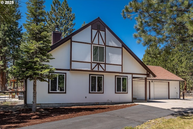 view of home's exterior with a chimney, stucco siding, fence, driveway, and an attached garage