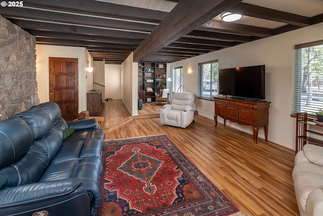 living area with baseboards, beamed ceiling, stairs, and wood finished floors