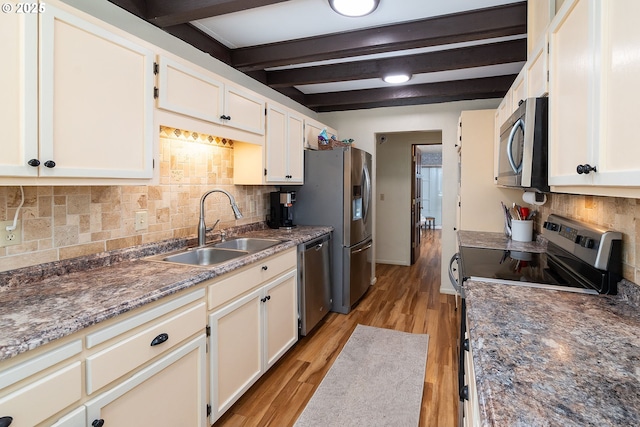 kitchen featuring a sink, beam ceiling, decorative backsplash, stainless steel appliances, and light wood-type flooring