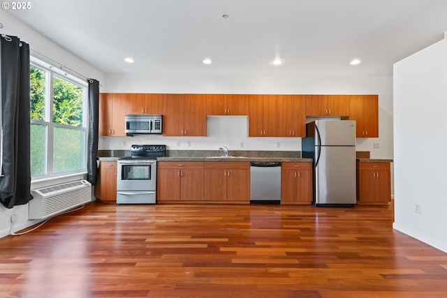 kitchen with brown cabinetry, a sink, dark wood-style flooring, and appliances with stainless steel finishes