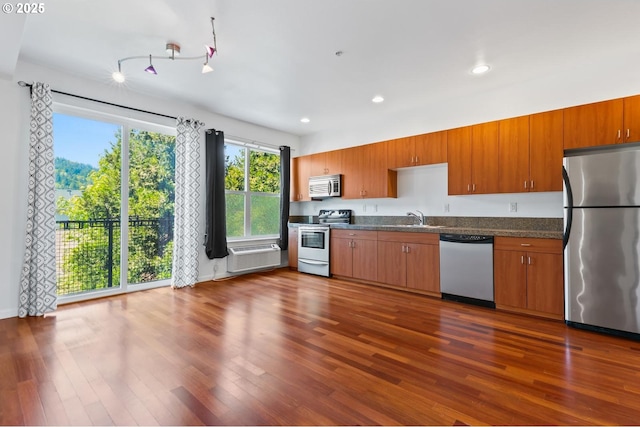 kitchen with dark countertops, dark wood-style floors, recessed lighting, a sink, and appliances with stainless steel finishes