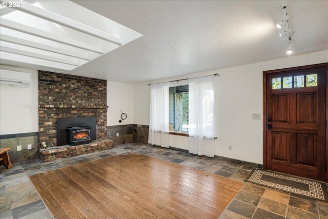 entrance foyer featuring track lighting, a wall unit AC, and a textured ceiling