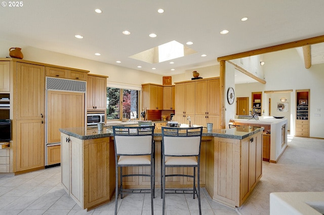 kitchen with a kitchen breakfast bar, recessed lighting, a large island with sink, a skylight, and paneled fridge