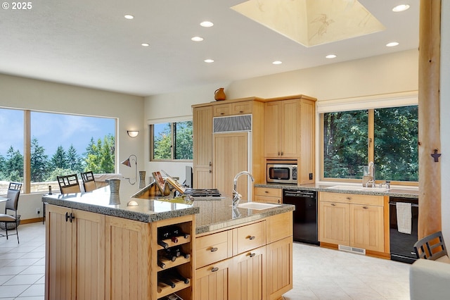 kitchen with visible vents, dishwasher, a sink, stainless steel microwave, and light brown cabinets