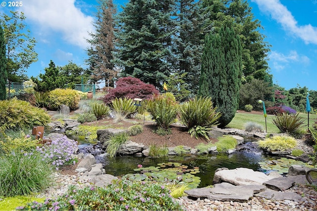view of yard featuring fence and a small pond
