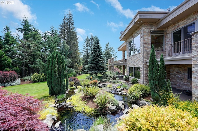 view of yard featuring a small pond, a balcony, and a patio area