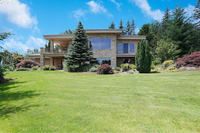 exterior space featuring a yard, a balcony, and stone siding