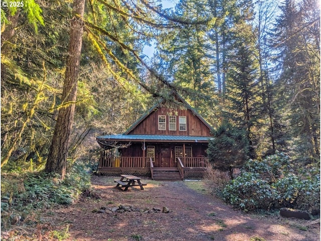 log home with a porch, metal roof, and a view of trees