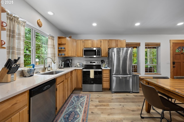 kitchen featuring a sink, light countertops, appliances with stainless steel finishes, open shelves, and light wood finished floors